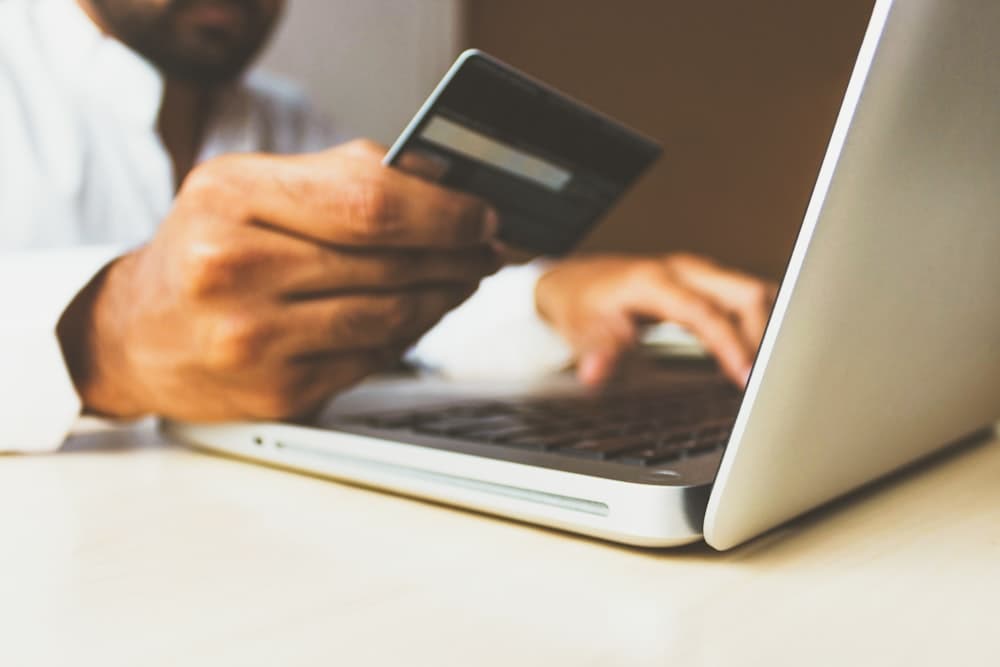 Hands using a bank card at a laptop